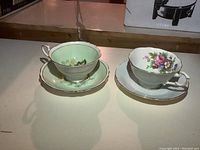 Two Paragon teacups with matching saucers displayed on a table, showing their floral patterns and gold trim.