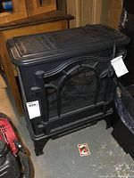 Front view of black metal electric fireplace showing mesh screen and arched design.
