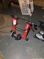 Full view of the red Minaura Mag500 exercise stand showing triangular frame, rubber feet, and resistance mechanism.
