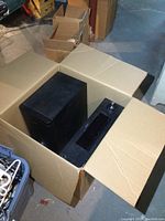 Photo showing the RCA AV receiver and black subwoofer in a cardboard box.
