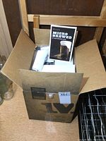 Open box showing 'Micro Brewed DIY Beer Brewing Guide' booklet and brewing components inside the box, including a white plastic part and sealed items.
