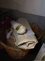 Five large nautical charts, mostly rolled, placed inside and around a large wicker basket.