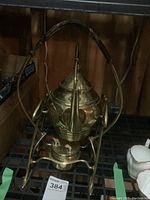 Front and side view of brass samovar with burner on metal shelving, showing curved spout, wrapped handle, and tripod burner base.