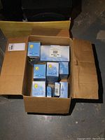 Six light blue boxes with sun/cloud graphics inside a cardboard shipping box containing new Ninja security camera accessories.