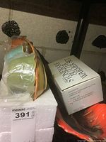 Photo showing boxed 3-piece stoneware butter warmer set alongside leaf-shaped serving dish on a shelf.