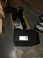 Samsung surround sound speakers set arranged on floor including subwoofer, front and rear speakers. Speaker wire visible.