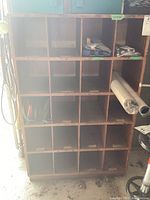 Front view of the wood cabinet showing 20 pigeonholes, some with tape residue. The cabinet is constructed of wood with a natural finish. Some small items are present but are excluded from sale.
