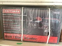 Boxed and sealed Craftsman belt and disc sander showing product branding, model number 928329, and dimensions of sanding belt and disc on packaging.