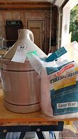 Photo of a beige ceramic crock with two black stripes and the chip on its upper rim, with a partially visible bag of Motomaster cheesecloth placed in front of it.