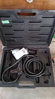 Electric tacker placed inside compartment of open black molded carrying case.