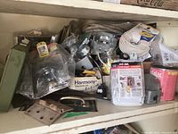 Wide view of various electrical and hardware items including cables, hinges, cable ties, junction boxes, mounting brackets and packaging from brands like Harmony and Red Dot.