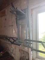 Metal garden tractor lift mounted vertically on wall, showing lifting platform and support bars.