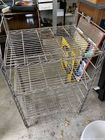 Metal 3-shelf wire grid utility rack placed in garage setting, showing overall condition and structure.