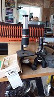 Photo showing two microscopes on a table along with a wooden slide box containing microscope slides, and a tag with lot information.