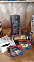 Photo of 4 Smart car models in original boxes, hardware truck model, and Vintage Wheels card game on wooden surface