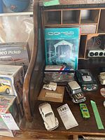 Overview of multiple model cars including Volkswagen Beetle, Jaguar, handmade ice cream truck, Corsa magazines, and other model cars stored on a wooden desk organizer.
