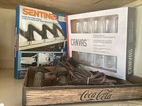 Sentinel roof de-icing cable box and Canvas brand Edison bulb garden string lights packaging and contents in wooden Coca-Cola box.