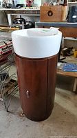 Full view of the vanity and sink showing cylindrical cognac-colored base and white ceramic top.