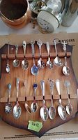 Collector spoons displayed on wooden board, showing all spoons with decorative handles