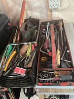 Two metal tool trays filled with assorted screwdrivers, wrenches, hammers, and other hand tools shown from above