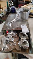 Photo of vintage metal cookie cutters in multiple shapes in a metal container along with an aluminum citrus juicer.