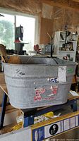 Front and side view of the vintage galvanized wash tub showing handles and sticker residue.