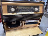 Open console showing radio tuner and turntable compartment with records
