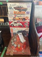 Photo of stacked vintage AMT model car kits and a set of model paints in a circular plastic tray.