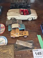 Overview of vintage metal model cars, showing four distinct cars in various colors and conditions, along with metal belt plates and buckle parts.
