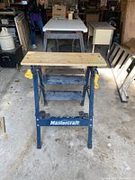 Front view of the work table showing metal blue frame and wooden top with holes