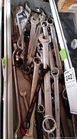 Drawer with assorted metal wrenches in various sizes and conditions, some shiny and others slightly rusted.