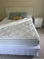 Queen bed with headboard, mattress and two night tables arranged side by side
