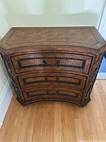 Front view of wooden end table showing three drawers with metal handles and leather look finish.