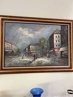 Framed giclee painting of a French street scene by Burnett, showing buildings, people, and a tree under a cloudy sky.
