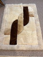 Full view of the cream, tan, and brown fur rug showing the overall geometric pattern and border.