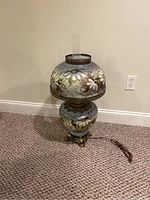 Full view of the hand-painted hurricane lamp showing floral decoration, metal base, and glass chimney.