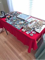 Wide view of table with mixed jewelry items including bracelets, necklaces, pins
