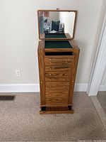 Full view of the jewelry chest with top open, showing green felt interior compartments and mirror.