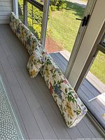 Shows the long floral bench cushion and matching pillow arranged on a porch bench.