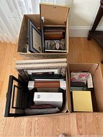 Overview of multiple cardboard boxes each filled with various picture frames of differing sizes and styles.