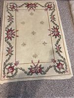 Top-down view of the entire cream wool rug showing floral border and center.