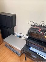 Photo of Bose speakers on left and stacked Sony stereo equipment with cables and manuals on top, JVC turntable beside them on the floor.