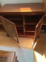 Wood cabinet with top view showing smooth surface, visible wood grain, and two doors, one with glass showing three shelves, other solid wood enclosing pull-out drawers.