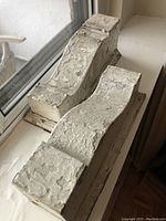 Pair of antique balustrade pieces used as bookends with chipped textured white paint finish shown from above and side angles.
