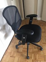 Side angle showing black mesh backrest, padded seat, and adjustable armrests of the office chair.