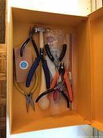 Overview photo of jewellery making tools in orange box with multiple pliers, cutters, and mandrel