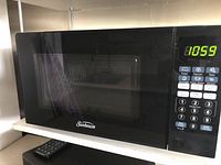 Front view of black Sunbeam microwave oven showing digital keypad and display.