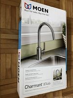 Box front showing Moen Charmant 87446 kitchen faucet product image and brand logo.