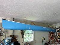 Side view of light blue We-no-nah canoe suspended indoors
