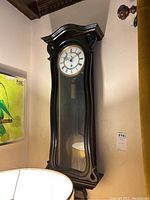 Full front view of wood wall clock showing dial and pendulum